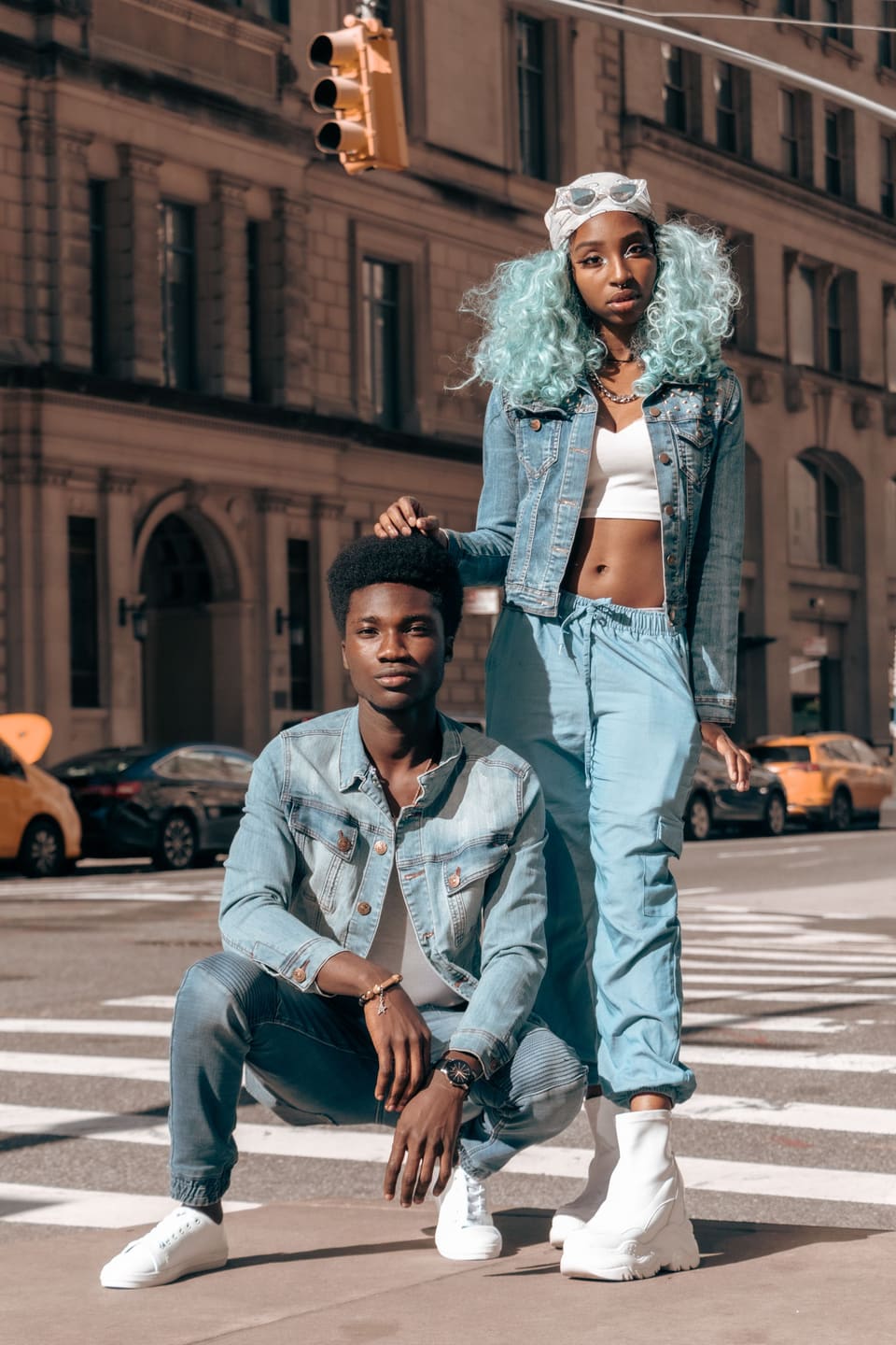 Double denim: Two models pose stylishly in denim outfits on a busy urban street, showcasing contemporary street fashion.