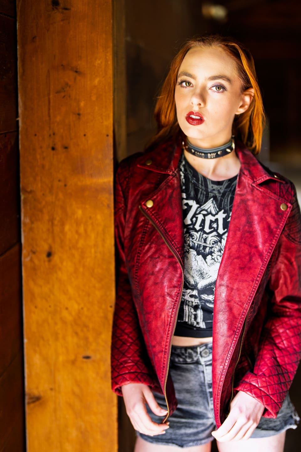 Rock & leather: Stylish woman wearing a red leather jacket and choker, posing indoors.
